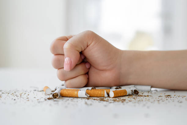 Iemand knijpt vastberaden een pakje sigaretten fijn — symbool voor de beslissing om te stoppen met roken