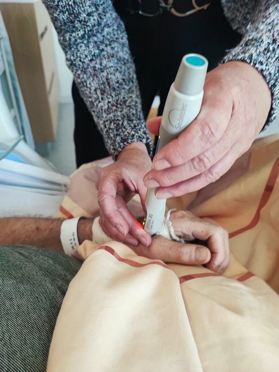 Close-up van een IRW-behandeling: infrarood licht wordt gericht op een acupunctuurpunt op het oor